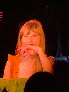 a woman sitting down with her hand on her chin