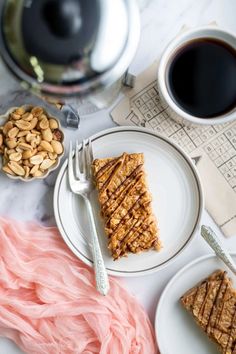 two plates with desserts on them next to a cup of coffee and saucer