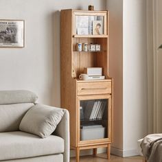 a living room with a white couch and a wooden cabinet in the corner next to a window