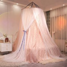 a pink canopy bed in a room with white walls and curtains on the ceiling,