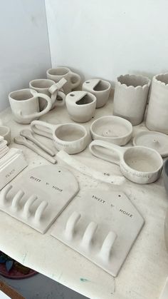 a table topped with lots of white pottery