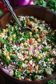 a wooden bowl filled with lots of food next to broccoli and other vegetables