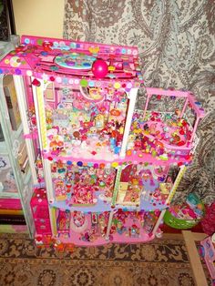 there is a pink doll house with lots of toys in the room next to it