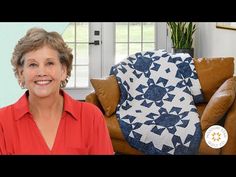 a woman sitting in front of a couch with a quilt on it