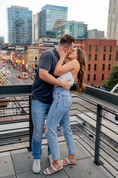 a man and woman kissing on top of a building