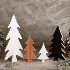 three wooden christmas trees are standing next to each other in front of snow covered ground