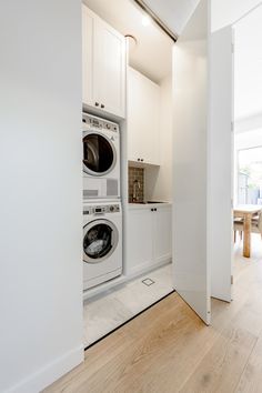 a washer and dryer in a room with white walls, wood flooring