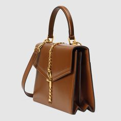 Description Designed with its original archetype in mind, the Sylvie 1969 unifies the details of its archival inspiration with a contemporary spirit. The structured top handle in textured brown leather is defined by a narrow gold-toned metal chain fitted to the flap and body of the bag—a modern interpretation of the distinctive hardware. The silhouette is completed with a detachable and adjustable shoulder strap. Size: 10.2″W x 7.7 “H x 3.3 “D / 25.9 x 19.5 x 8.3 cm ; Brown textured leather with Gucci Top Handle Bag, Small Top Handle Bag, Gucci Sylvie, Structured Top, Gucci Store, Gucci Gifts, Handle Bag, 7 H, Small Tops