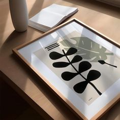 a table with a vase, fork and spoon on it next to an art print