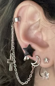 a close up of a person's ear with chains and stars attached to it