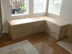 a wooden bench sitting on top of a hard wood floor next to two large windows