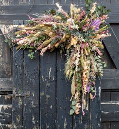 a wreath made out of dried flowers hangs on an old door