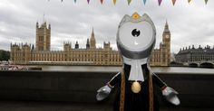 an inflatable cat is sitting on the side of a building with big ben in the background