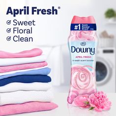 a bottle of downy dishwasher deterant next to folded towels and a pink flower