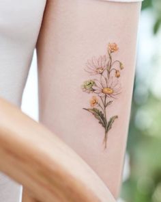 a woman's arm with flowers tattooed on it