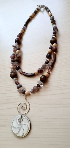 "Fibonacci Multi Stone Agate Bohemian Necklace by GlamRox. Fibonacci Shell Pendant. Multi Gemstone Botswana Agate Wood Necklace Boho Stunning Double Strand Bib Drop Long Necklace comprise of genuine Botswana Agate, Wood, Rutilated Quartz and Czech Glass featuring a stunning drop of a Fibonacci Spiral and Carved Mother of Pearl Pendant! Truly beautiful on and so unique. Hand made and designed by yours truly, GlamRox Necklace measures: 21 inches long Pendant Section: 3.5 inches long Don't miss out Handmade Brown Double Strand Jewelry, Brown Spiral Necklace For Gifts, Handmade Spiral Brown Jewelry, Unique Brown Spiral Jewelry, Bohemian Spiral Jewelry For Healing, Brown Spiral Jewelry As A Gift, Elegant Brown Jewelry For Meditation, Fibonacci Shell, Fibonacci Spiral