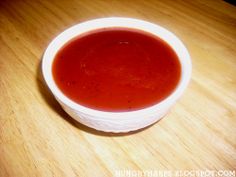 a bowl of tomato soup sitting on top of a wooden table