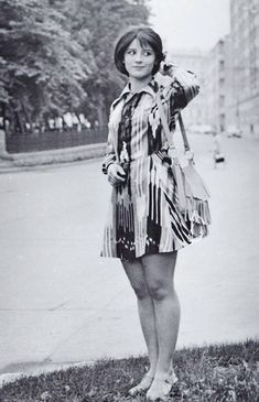 an old photo of a woman standing in the grass with her hand on her head