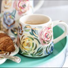 a croissant on a plate next to a cup of coffee and a croissant