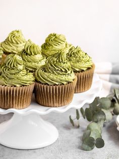 cupcakes with green frosting sitting on a cake plate