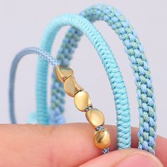 a person holding two different colored bracelets in their left hand and one with gold beads on it