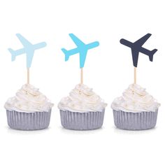 three cupcakes with blue and white frosting in front of an airplane on top