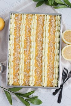 a close up of a cake on a table with lemons and utensils