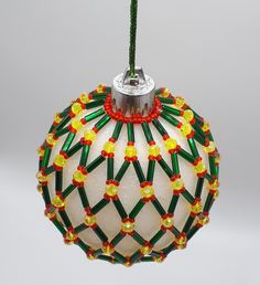 a glass ornament hanging from a green string with red, yellow and green beads