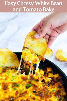 a hand holding a piece of cheesy white bean and tomato bake over a skillet