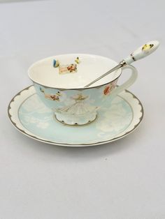 a tea cup and saucer with a spoon in the shape of a boat on it