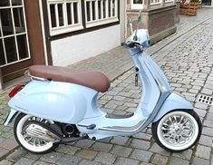 a blue scooter parked on the side of a street next to a building