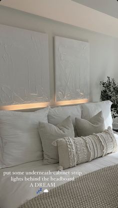 a bed with white pillows and two paintings on the wall