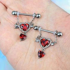 a pair of red heart shaped dangling belly rings