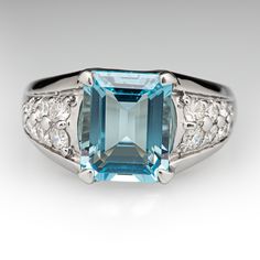 This cool-hued ring is centered with one (1) emerald cut natural aquamarine set into a four-prong setting. The shoulders of the ring are each accented with eight (8) shared bead set round brilliant cut diamonds. The ring measures 10.7mm at the top, rises 6.7mm above the finger, and tapers to 2.9mm wide by 1.0mm thick at the base of the shank. The ring is crafted in platinum and is currently a size 6.25. Classic Topaz Ring With Octagon Prong Setting, Classic Octagon Topaz Ring With Prong Setting, Classic Topaz Gemstones With Accent Stones, Elegant Baguette Cut Topaz Ring With Accent Stones, Turquoise Topaz Ring With Center Aquamarine Stone, Elegant Blue Topaz Gemstone With Center Stone, Elegant Emerald Cut Gemstones With Accent Stones, Elegant Emerald Cut Platinum Gemstone, Fine Jewelry Aquamarine Diamond Ring With Gemstone