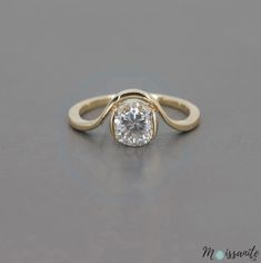 a yellow gold engagement ring with a round diamond in the center, on a gray surface