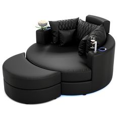 a black couch with two pillows on it and an electronic device next to it, sitting in front of a white background