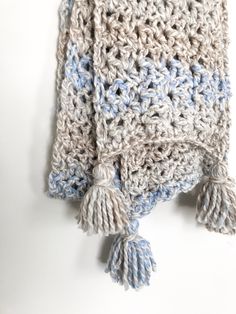 a crocheted blanket with tassels hanging from it