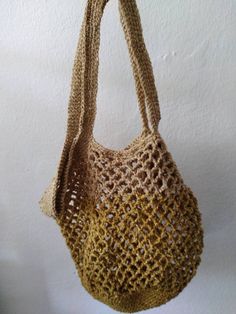 a crocheted handbag hanging from a hook on a wall with white walls in the background