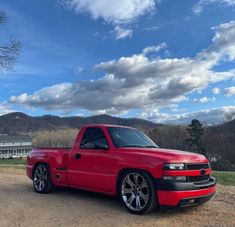 a red truck parked on top of a dirt road