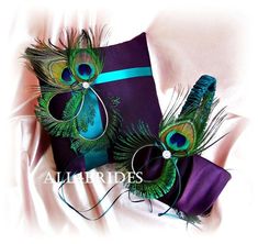 two peacock feathers are on top of a purple pillow