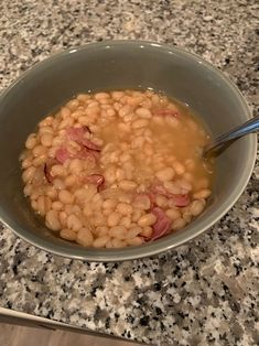 a bowl filled with beans and ham on top of a counter