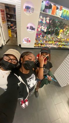 three people wearing masks and standing in front of a store display with their hands on their mouths