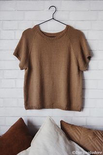 a brown sweater hanging on a white brick wall next to pillows and throw pillows in front of it