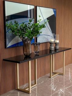 two vases filled with plants on top of a table next to a wall mounted painting