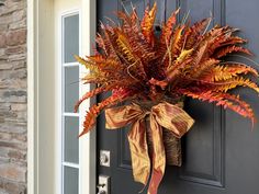 a wreath on the front door decorated with autumn foliage