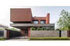 a modern house with brick walls and windows on the outside, surrounded by greenery