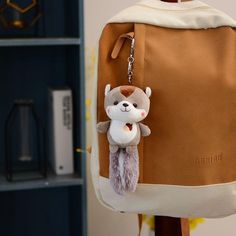 a brown and white backpack with a small stuffed animal on it's back pocket