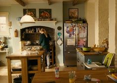 a woman standing in a kitchen next to a stove top oven and refrigerator freezer