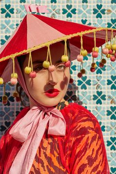 a woman wearing a red hat with tassels on it's head and eyes