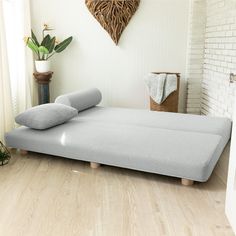 a bed with two pillows sitting on top of it next to a brick wall and potted plant